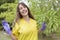 Portrait of young and smiling doctor happily holding with her hands a stethoscope. She is outdoors in nature