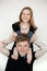 Portrait of young smiling family in dark clothes with plump cherubic baby infant toddler standing on white background.