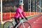 Portrait of Young Smiling Female Cyclist in Pink Jacket Resting with Road Bicycle in the Cold Sunny Autumn Day