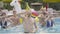 Portrait of young smiling man in party hat dancing in water pool with multiethnic people repeating movements at the