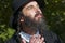 Portrait of young smiling praying orthodox Jewish man looking up