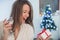 Portrait of young smiling woman in decorated living room with gi