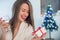 Portrait of young smiling woman in decorated living room with gifts and Christmas tree.