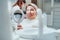 Portrait of young smiling woman sitting in stomatology clinic chair and looked at mirror evaluating her teeth after Tooth