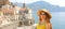 Portrait of young smiling woman with sunglasses in Atrani village, Amalfi Coast, Italy. Panoramic banner view of female tourist i