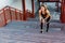 Portrait of young sporty girl in black sportwear standing on stairs and have strong hurt problem with knee, spasm painful.