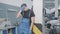 Portrait of young stressed auto mechanic standing in repair shop holding head in hands. Unhappy brunette Caucasian