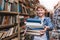 Portrait of a young student offering a book.man with lots of books in his hands is in the library and smiles