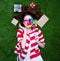 Portrait of a young styled redhead woman with pinwheel toy present around lying down on green spring grass, above point of view