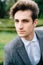 Portrait of young stylish groom in gray suit looking pensively at the camera