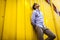 Portrait of young stylish man standing against yellow wall outdoors. Summer fashionable outfit.