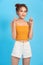 Portrait of young stylish woman in crop-top pointing fingers up, smiling and look amused, interested, found product, show promo