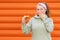 Portrait of a young surprised woman with dreadlocks holding a stack of dried fruits. Orange background. Concept of