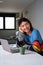 Portrait of young taiwanese man smiling and working at home with a laptop.