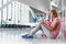 Portrait of young teenage girl sitting on the floor and using digital tablet while waiting for her flight in airport