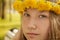 Portrait of young teenager girl on bench with wreath of dandelions