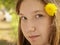 Portrait of young teenager girl in park with dandelion in hair