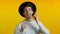 Portrait of young thinking pondering man in hat having idea moment pointing finger up on yellow studio background