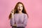 Portrait of young thinking pondering woman having idea moment pointing finger up on pink studio background. Smiling