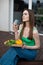 Portrait of young thoughtful gorgeous woman sitting on step of wooden veranda, holding glass of wine, cut vegetables.