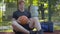 Portrait of young thoughtful redhead man sitting with ball on basketball court. Sad Caucasian lonely sportsman after