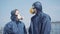 Portrait of young tired couple in respirators strolling outdoors and chatting. Man and woman in chemical suits talking