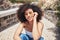 Portrait of young trendy beautiful mixed race woman with an afro smiling and posing alone outside. Hispanic woman