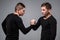 Portrait of young twin brothers standing face to face on gray ba