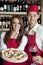 Portrait of a young wait staff with wine glass and pizza