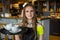 Portrait young waitress standing in cafe. girl the waiter holds in bunches a tray with utensils