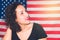 Portrait young woman with the American flag in the background and staring blankly