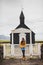 Portrait of young woman on Background of Famous black church of Budir in Iceland