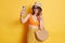 Portrait of young woman blogger wearing summer clothing with straw bag standing making selfie, live stream, showing v sign to