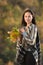 Portrait of young woman with a bouquet of autumn leaves. Cozy autumn. Vertical frame