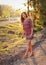 Portrait of young woman in casual summer dress, strong sunset backlight with nice bokeh, blurred trees and river background