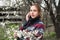 Portrait of a young woman in cold spring outdoors. White flowers