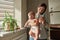 Portrait of young woman and cute little child in home interior