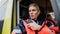 Portrait of young woman doctor sitting and talking in to walkie-talkie in ambulance car.