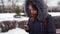 Portrait of young woman flipping news in smartphone in countryside in winter season. Adult female in hooded jacket comments on the