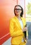 Portrait of young woman in glasses, yellow suit with folder