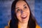 Portrait of young woman with grimacing face. Close up of crazy female in yellow hoodie monkeying on gray brick