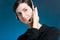 Portrait of young woman with headset, on blue background, smiling