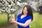 Portrait of a young woman holding a brunch of blossoming plum tree in an orchard