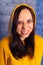 Portrait of young woman in hood with grimacing face. Close up of funny female in yellow hoodie monkeying on gray brick