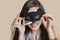 Portrait of a young woman imitating as cat while looking through eye mask over colored background