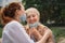 Portrait of young woman kissing grandmother outdoors in city, life after covid-19 vaccination.