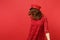 Portrait of young woman in lace dress and cap standing, jumping with fluttering hair isolated on bright red wall