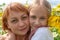 Portrait of a young woman and little girl outdoors.Sweet little girl is hugging her beautiful young mom standing in a large field