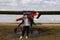 Portrait of young woman near the retro plane. field with plane flying over it