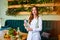 Portrait of a young woman nutritionist in medical gown standing with clipboard and tape measure in the office with healthy food on